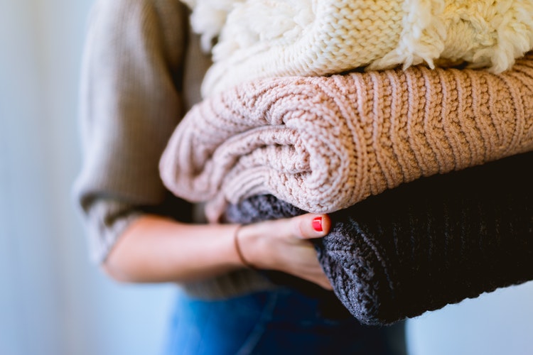 идеи за есенни снимки за инстаграм - момиче със сгънати пуловери в ръце